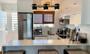 a kitchen with white cabinets and a large counter top at Abode Africa in Bloubergstrand