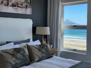 a bedroom with a bed and a view of the beach at Abode Africa in Bloubergstrand