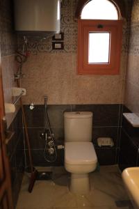 a small bathroom with a toilet and a window at Kana Kato in Aswan