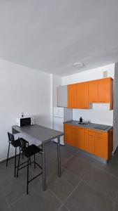 eine Küche mit einem Tisch und einigen orangefarbenen Schränken in der Unterkunft Chez Frois in Las Palmas de Gran Canaria