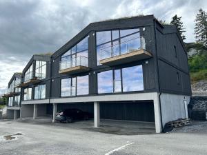 una casa negra con un coche aparcado en un estacionamiento en Ny leilighet på Norefjell - ski in/out en Noresund