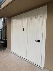 una grande porta bianca del garage con manico nero di Case Stevanato appartamento Mia a Noale
