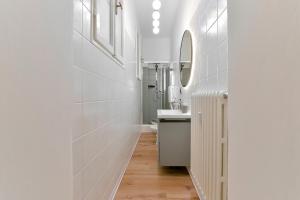 een witte badkamer met een wastafel en een spiegel bij MONO Apartments Saragozza in Bologna +8 foto's
