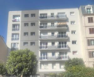 een hoog wit appartementencomplex met balkons bij Le SerenityAppart Suresnes in Suresnes