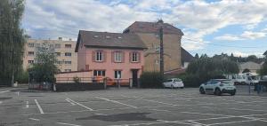 a parking lot with cars parked in front of a pink building at Cramiland - Chambre d'hôte chez nous in Montbéliard