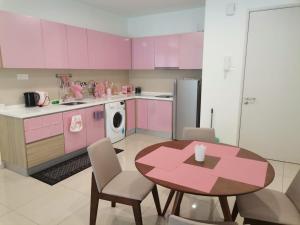 een keuken met roze kasten en een tafel met stoelen bij I-Suite Block B [2r2b] # I-City [ Free Wifi + Parking ] in Shah Alam