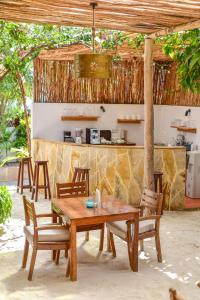 a wooden table and chairs in front of a kitchen at Barabara house in Jambiani