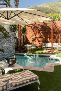 a swimming pool with an umbrella and a table at Sweet Orange Guest House in Cape Town