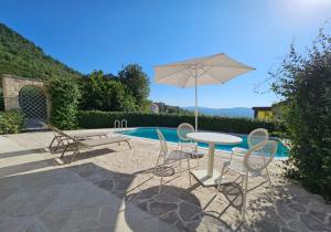 uma mesa e cadeiras com um guarda-sol ao lado de uma piscina em Villa Ava Kotor em Kotor