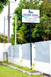 a sign for a home home sign in front of a fence at Rhome Home in Weligama