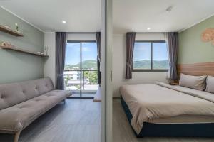 a bedroom with a bed and a couch and windows at New Condo,Great View,A* Location in Ban Klang