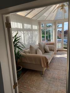 un soggiorno con divano in una camera con finestre di Rose Cottage Glastonbury a Glastonbury