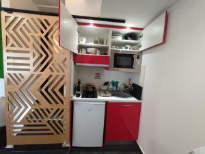 a small kitchen with red cabinets and a wooden door at THEASIS 4 luxury studio with sea view in Neos Marmaras