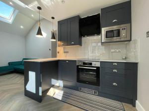 une cuisine avec des armoires noires et un four micro-ondes dans l'établissement Stunning semi detached bungalow in West Wimbledon, à Londres