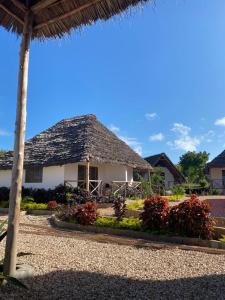 a white house with a straw roof at Kokopelli Bungalows in Nungwi