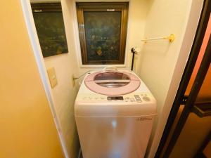 a washing machine in a small bathroom with a window at Yama house in Tokyo
