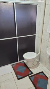 ein Badezimmer mit einem WC und einer Dusche mit Matten in der Unterkunft Pousada 4 Estações in Lauro Müller
