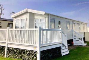 a white house with a porch and a white railing at Church Point holiday park, Newbiggin by the sea Northumberland in Newbiggin-by-the-Sea