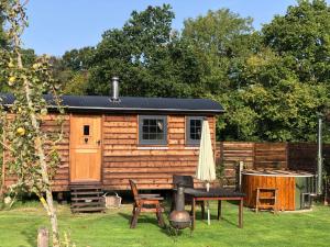 a log cabin with a table and a grill at Goodwin Farm in Northiam