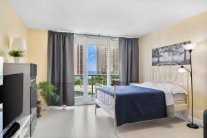 um quarto com uma cama, uma televisão e janelas em OCEAN RESERVE APARTMENt em Miami Beach