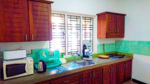 cocina con armarios de madera, fregadero y microondas en Rhome Home, en Weligama