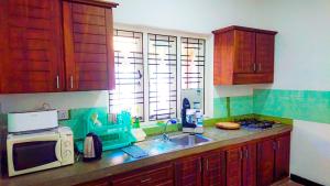 a kitchen with wooden cabinets and a sink and a microwave at Rhome Home in Weligama