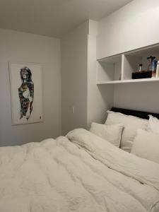 um quarto com uma cama branca e uma fotografia na parede em Modern apartment nearby city centrum em Tromsø