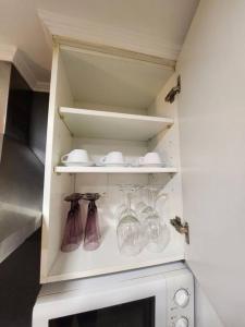 a kitchen cabinet with wine glasses and a microwave at El Apartamento in Ateca