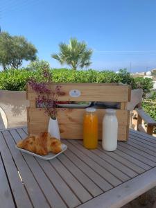 Coralli Beach Apartments في ميكري فيغلا: طاولة مع صحن من الخبز وزجاجات من عصير البرتقال