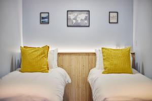 two beds with yellow pillows sitting next to each other at South Bay Garden Apartment in Scarborough