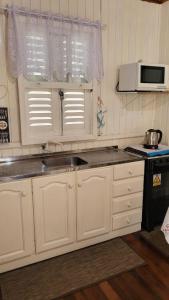 kuchnia z białymi szafkami, zlewem i kuchenką mikrofalową w obiekcie 4Estações w mieście Lauro Müller