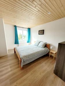 Schlafzimmer mit einem großen Bett und blauen Vorhängen in der Unterkunft Gîte des Rondins in Aumontzey