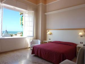 a bedroom with a red bed and a large window at Hotel Liberty in Viareggio