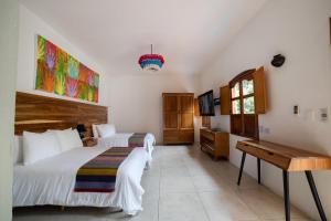 a bedroom with two beds and a desk and a television at NaNa Vida Hotel Oaxaca in Oaxaca City