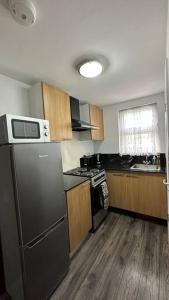 a kitchen with a stainless steel refrigerator and wooden cabinets at Palaz 8 - One Bedroom Flat in Edmonton