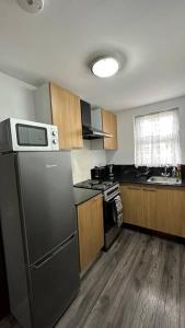 a kitchen with a black refrigerator and wooden cabinets at Palaz 8 - One Bedroom Flat in Edmonton