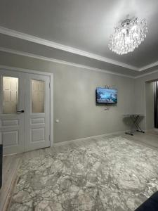 uma sala de estar com um lustre e uma televisão no tecto em Apartment in street Toktogula 77 em Bishkek