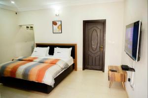 a bedroom with a bed and a brown door at Duke Diamonds Apartments in Abuja