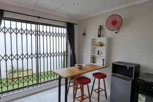 cocina con mesa y sillas y ventana grande en Cosy Carlisle, en Port Elizabeth