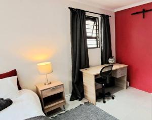 1 dormitorio con escritorio, 1 cama y ventana en Cosy Carlisle, en Port Elizabeth