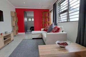 salon z białą kanapą i czerwoną ścianą w obiekcie Cosy Carlisle w mieście Port Elizabeth