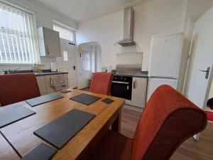 uma cozinha com uma mesa de madeira com cadeiras e uma sala de jantar em Maryann's em Huddersfield