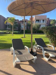 2 Liegestühle unter einem Sonnenschirm auf einer Terrasse in der Unterkunft Appartement de luxe Prestigia Opale 
