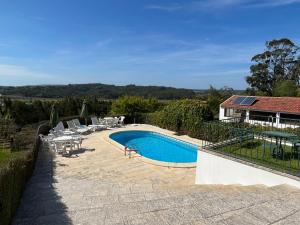 a swimming pool with chairs and a house at Casa da Quinta do Outeiro in Reveles