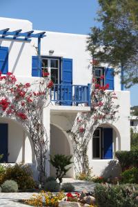 un edificio blanco con ventanas azules y flores en Paros Inn, en Logaras