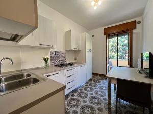 uma cozinha com armários brancos, um lavatório e uma janela em All'ombra del Carmine em Pádua
