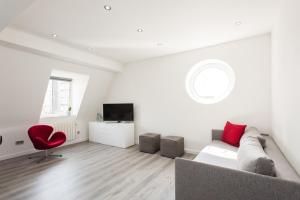 a white living room with a couch and a red chair at Welcome London Carnaby Street in London