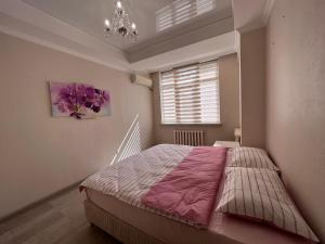 - une chambre avec un lit avec une couette rose et une fenêtre dans l'établissement Абрикос, à Bishkek