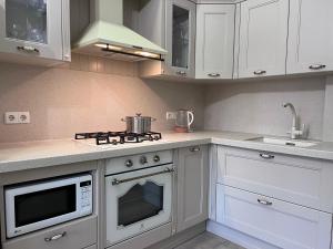 a kitchen with white cabinets and a stove top oven at Абрикос in Bishkek