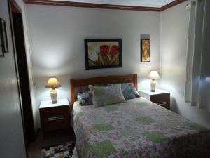 a bedroom with a bed and two night stands with lamps at CASA DA FAMÍLIA DE GRAMADO in Gramado